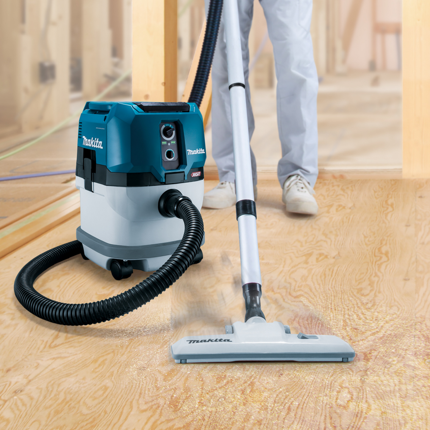 Makita vacuum cleaner on a wooden floor with a person cleaning.