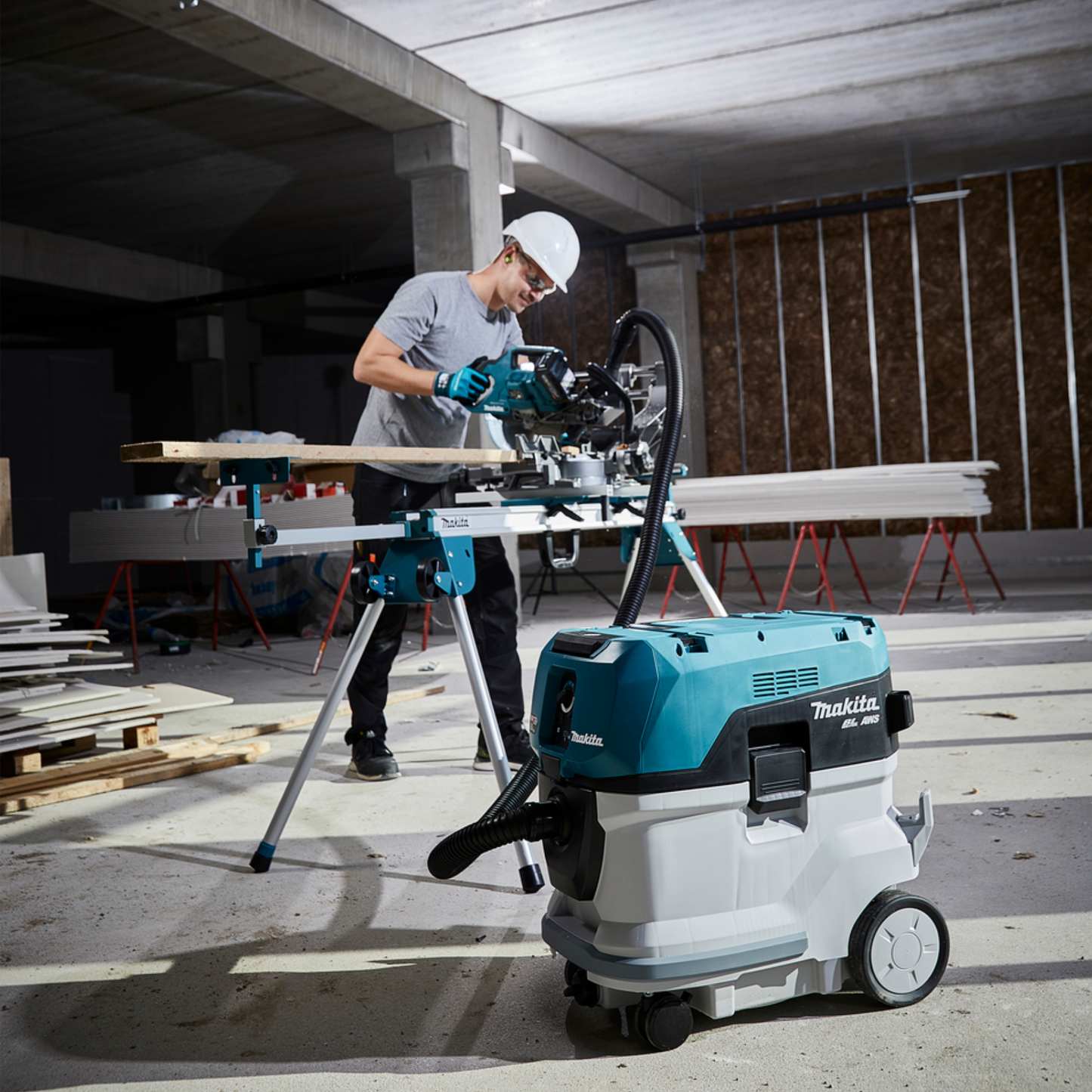 Person using a Makita power tool in a construction setting with a dust extractor.