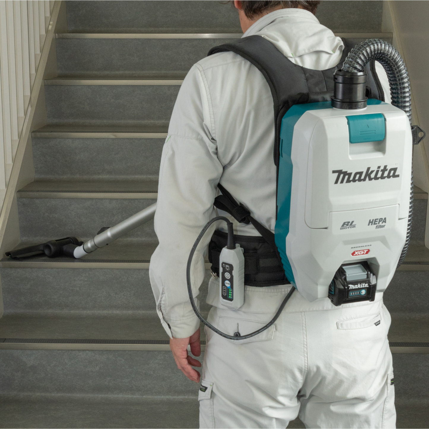 Person using a Makita backpack vacuum tool on a staircase