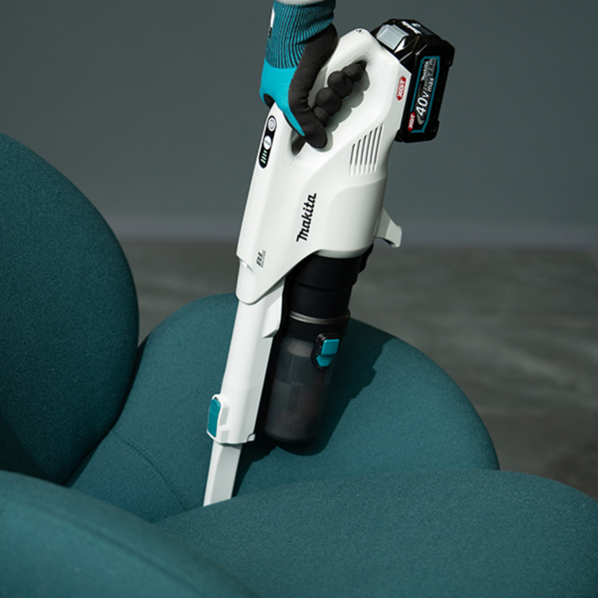 Makita vacuum cleaner on a teal cushion with a gray background