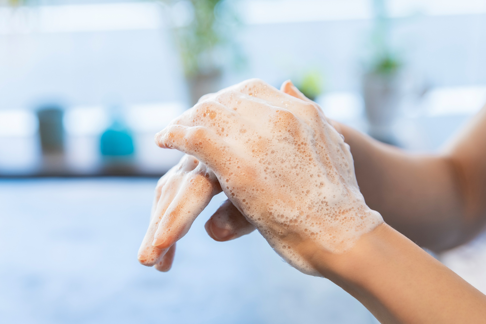 Hand washing with soap and water in a blurred indoor setting