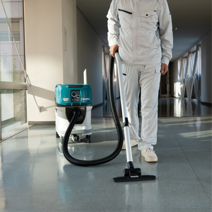 Person in white cleaning suit using a vacuum cleaner on a polished floor.