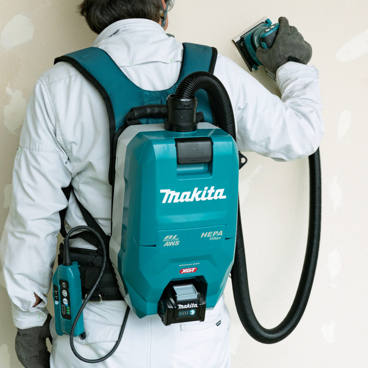 Person using a Makita backpack vacuum cleaner with a HEPA filter on a plain background