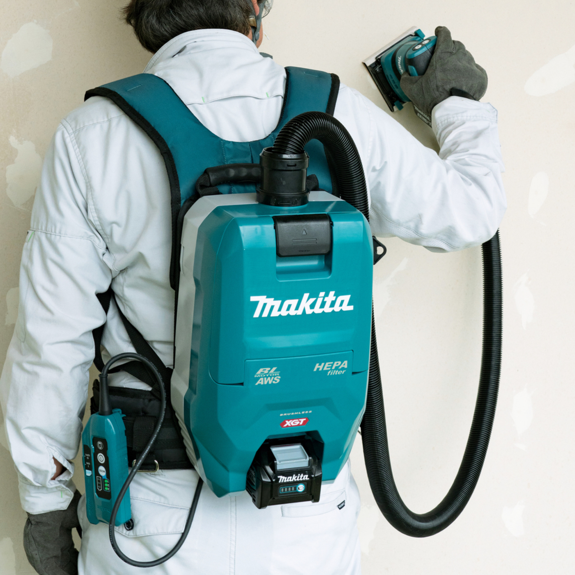 Person using a Makita backpack vacuum cleaner with a HEPA filter on a plain background