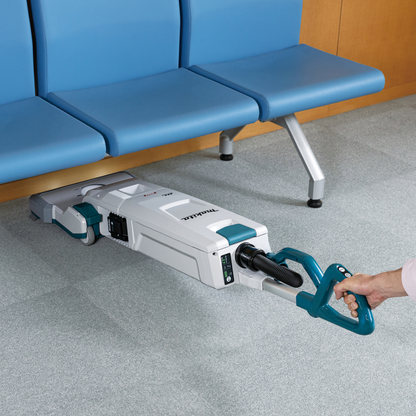 Person using a carpet cleaning machine on a gray floor with blue chairs in the background